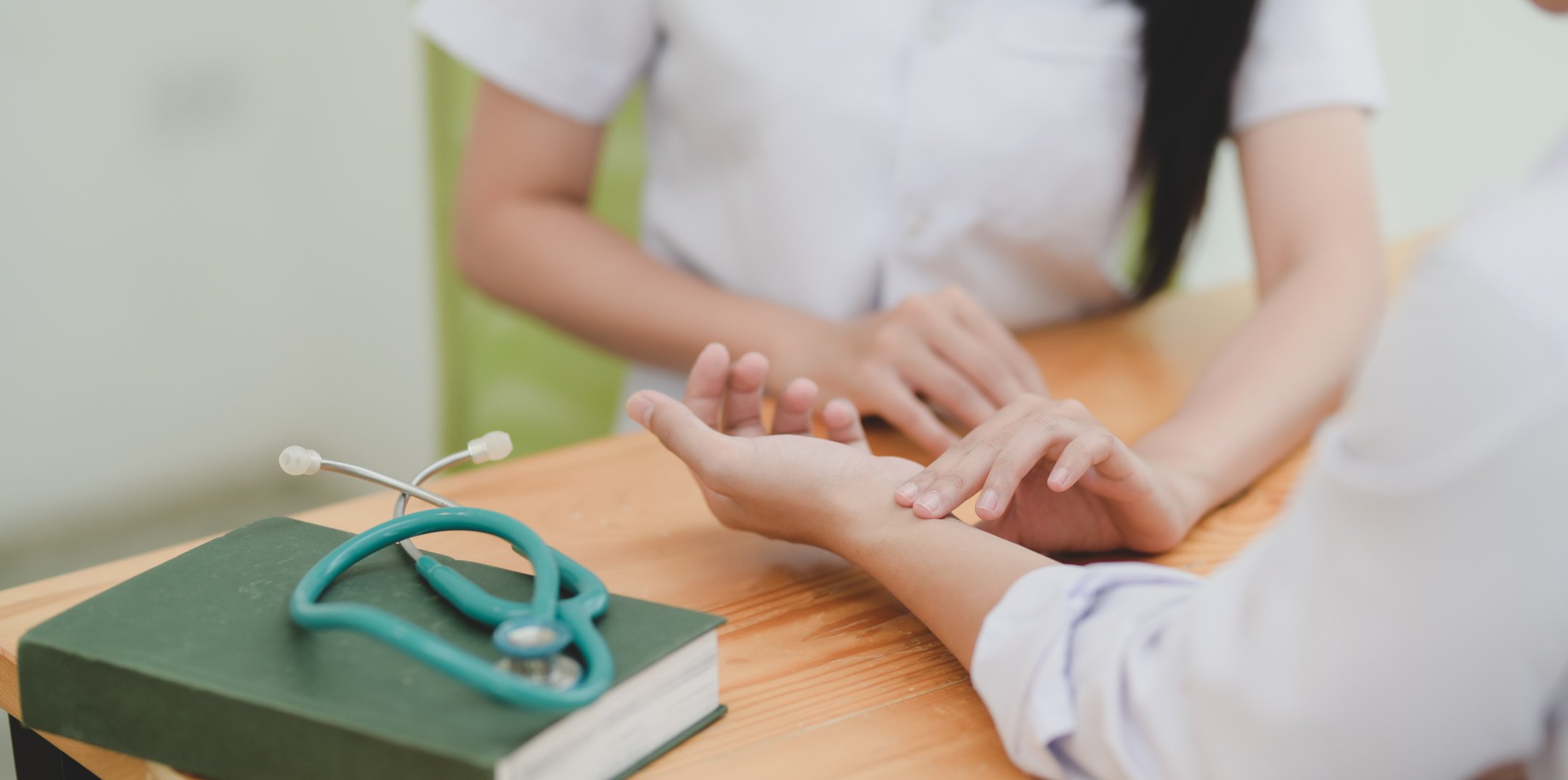 Crop nurse checking patients pulse in clinic